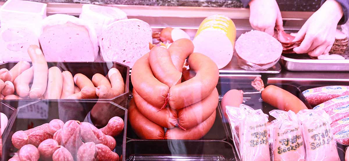 Auswahl an Wurstprodukten in der Wursttheke, einschließlich verschiedener Sorten wie Salami und Fleischwurst.